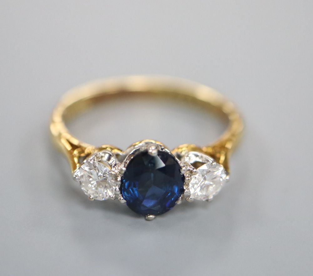 A modern 18ct gold, sapphire and diamond three stone ring, size L, gross 3 grams.